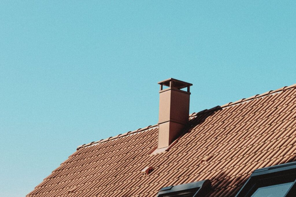 Rött betongtak och skorsten mot blå himmel.